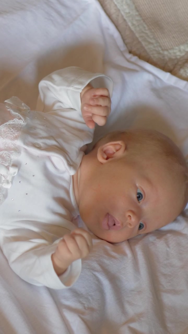 Bayi perempuan aktif berusia dua bulan yang terjaga di tempat tidur