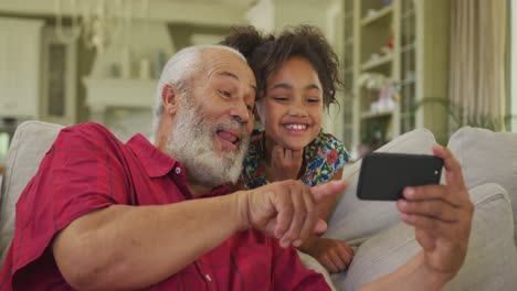 abuelo y nieta usando un teléfono inteligente en casa