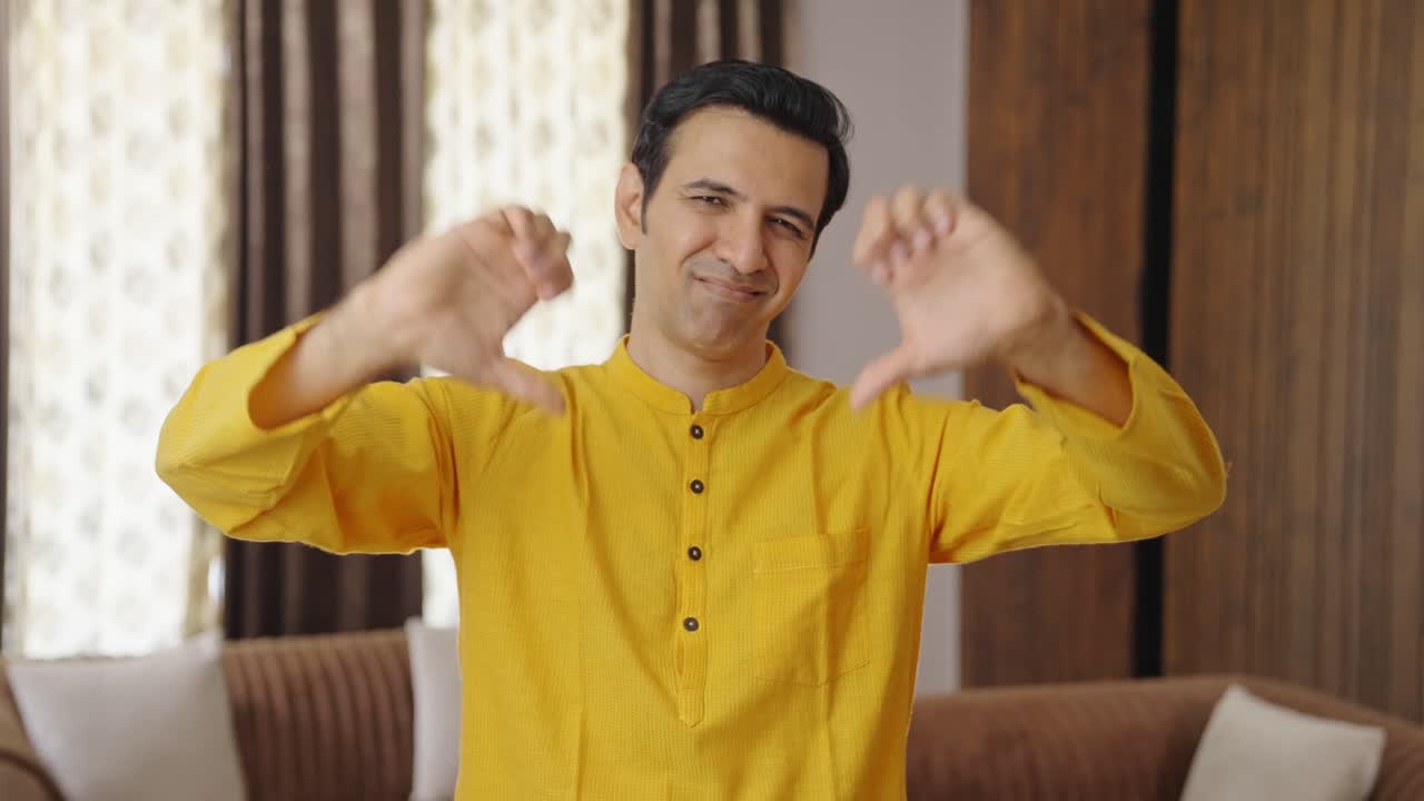 혐오스러운 인도인 남자가 엄지손가락을 내려놓고 있습니다.