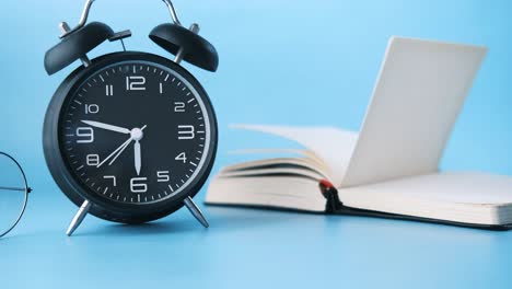 alarm clock, open book, and glasses