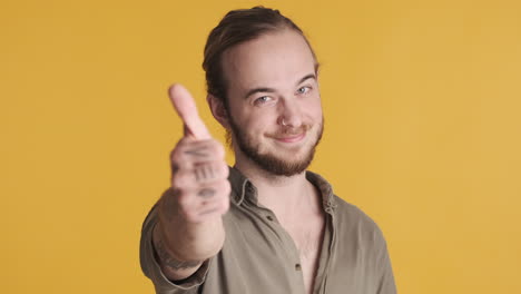 caucasian young man showing thumb up to the camera.