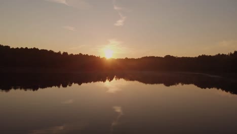 Person-Rowing-Boat-On-The-Calm-Lake-During-A-Golden-Sunset-In-Rogowko,-Poland