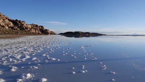 pan to glassy reflective surface of uyuni salt lake, bolivian plateau