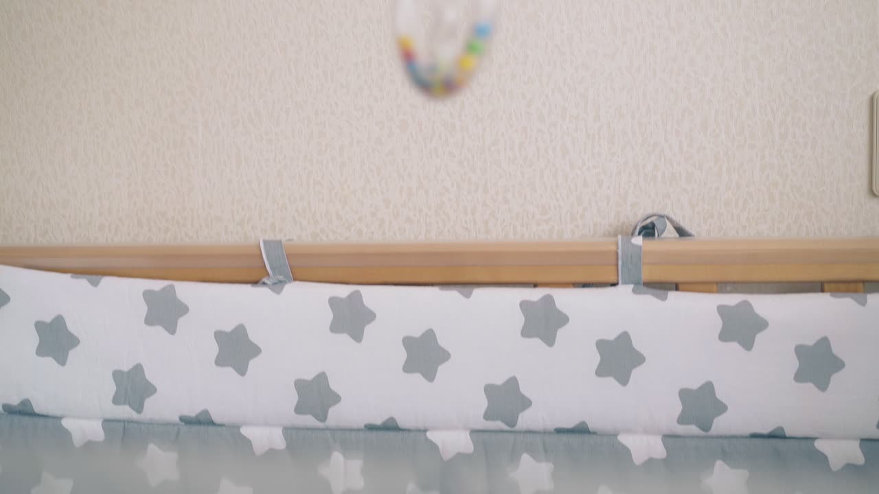 il bambino piccolo guarda il sonagliante nella mano della madre che giace nel bozzolo