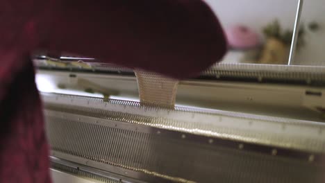 female hands making weaving pattern on knitting machine in textile workshop