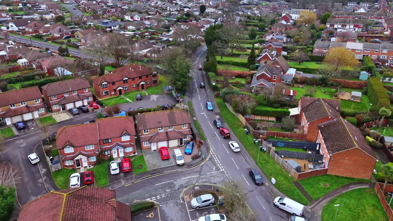 aerial panning drone shot over a suburban neighbourhood in Southampton, Hampshire named Hedge end. Shot on a quiet sunset on a cloudy winters day with many houses, fields and cars on the roads below