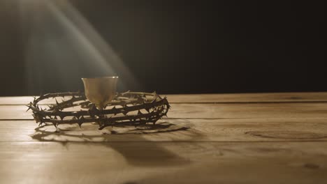 concepto religioso toma de cáliz con corona de espinas colocada alrededor sobre fondo de madera