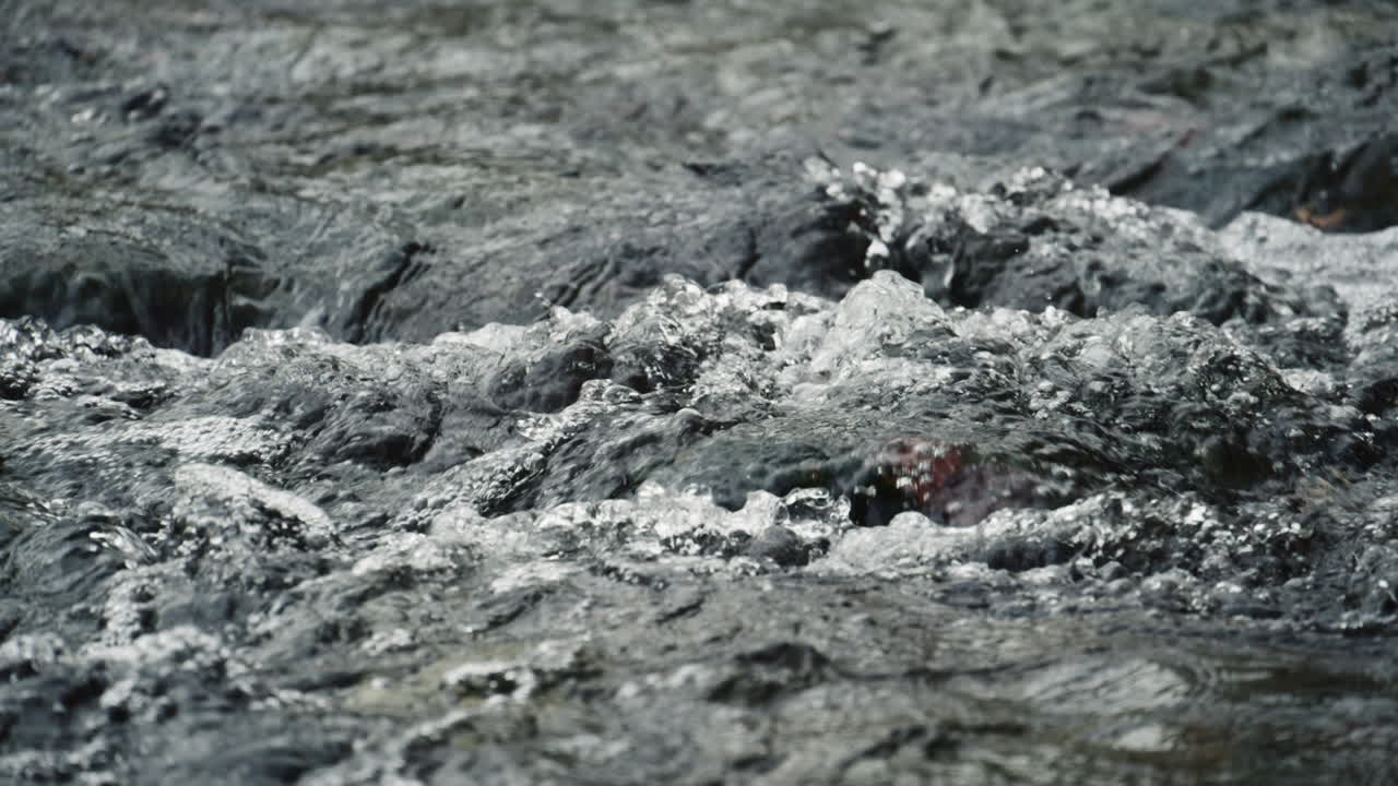 Primo piano dell'acqua impetuosa di un fiume che scorre sulle rocce creando schiuma e spruzzi. Parco Nazionale dei Laghi di Plitvice, Croazia