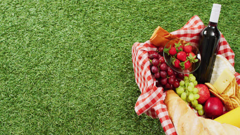 video of fresh bread, grapes and wine in basket and gingham tablecloth with copy space on grass