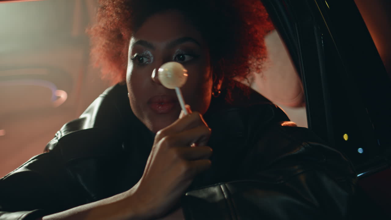 Sensual woman licking candy at evening rest in car closeup. lady enjoy
