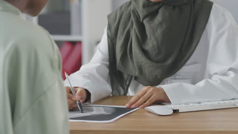 Female-Doctor-Or-Consultant-Wearing-Headscarf-Having-Meeting-With-Female-Patient-To-Discuss-Scans