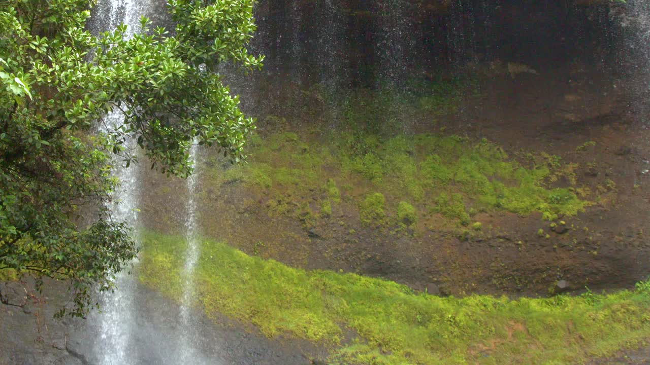 A wide shot pans down the cascading Ngardmau waterfall surrounded by lush tropical rainforest greenery