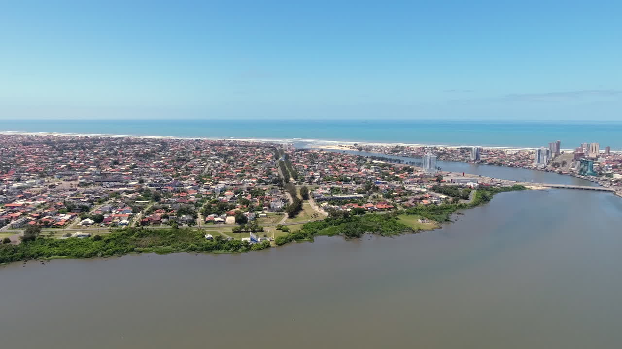 Panoraamailmakuva Imbestä, silta Tramandaí-joen yli ja Tramandaín rannikon siluetti Etelä-Brasiliassa.