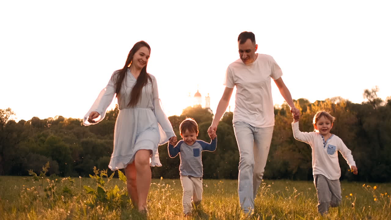 feliz familia su hombre con dos hijos caminando por el campo al atardecer en la luz del atardecer en el verano en clima cálido.
