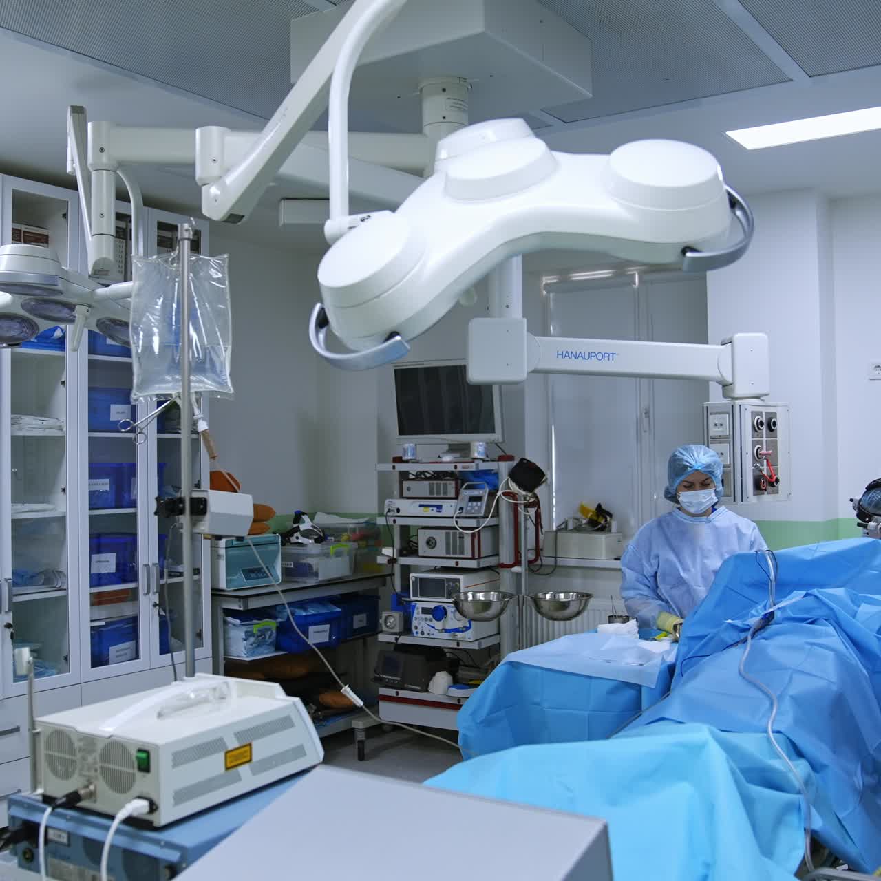 Modern surgery room with advanced equipment. Surgeon sitting at the patient performs operation assisted by nurse