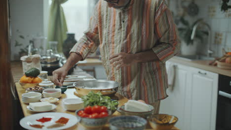 indian chef adding salt to bowl and explaining recipe during cooking class