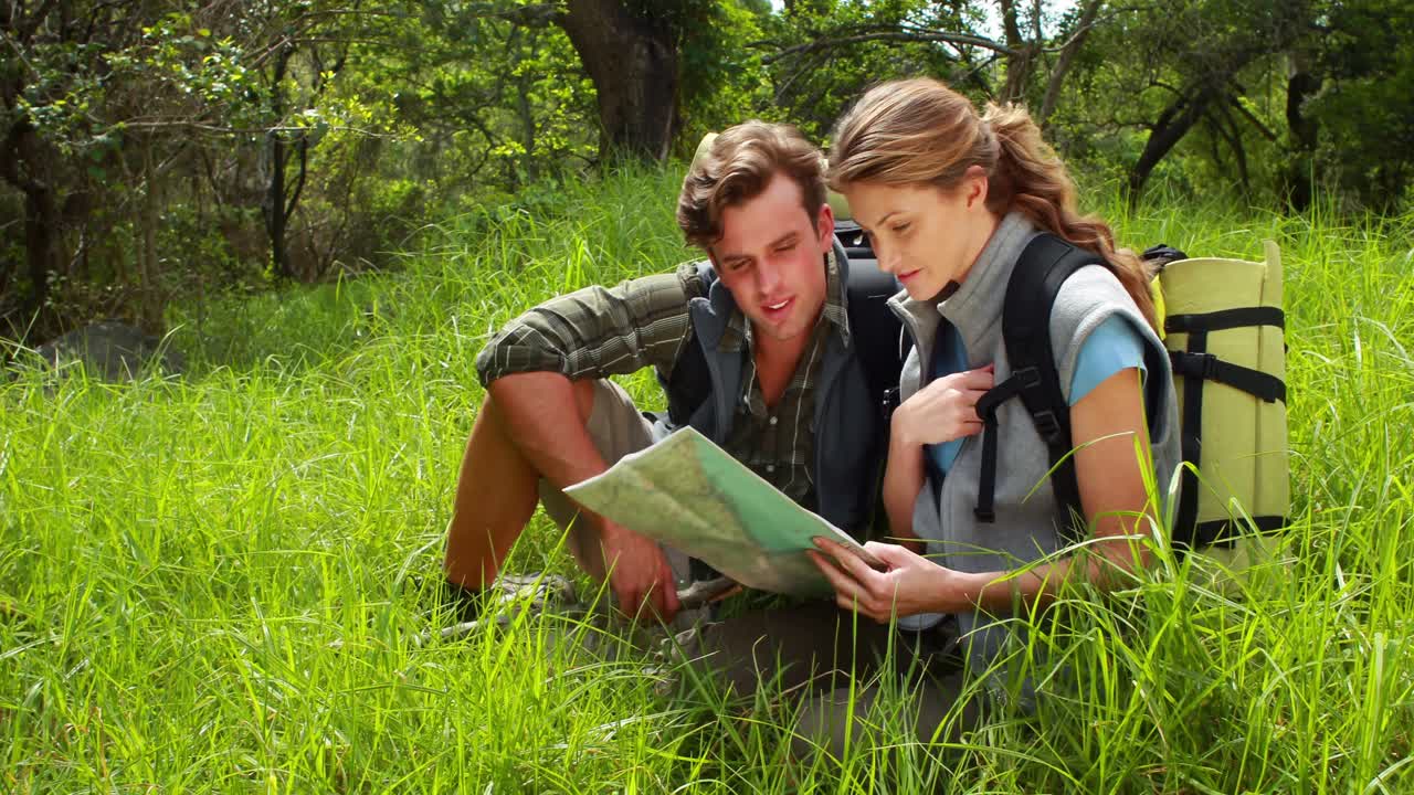 pareja de excursionistas con un mapa que apunta hacia adelante