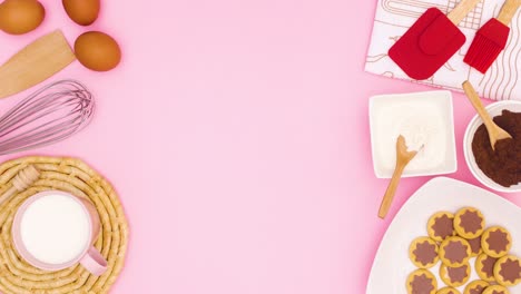 items for making cookies and cookies in plate appear on left and right side of pink theme. stop motion