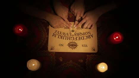 ouija board with hands and candles