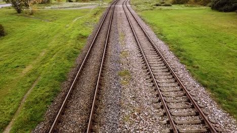 Aerial forward of two old rubble train tracks with grass and tree aside