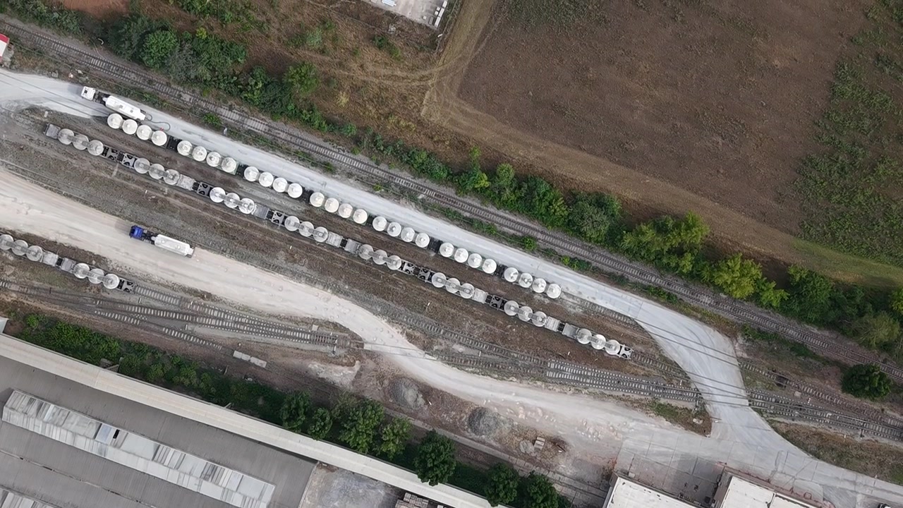 An aerial drone shot reveals an active industrial complex with roads, rail lines, and buildings, showcasing vital logistics and urban infrastructure.