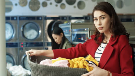 Portrait-Of-Beautiful-Stylish-Woman-Smiling-To-Camera-And-Holding-Basket-With-Dirty-Clothes-While-Standing-In-Laundry-Service