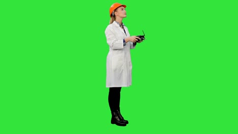 ingeniera femenina corrige partes de un objeto usando un control remoto en una pantalla verde, tecla de croma
