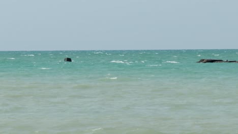 waves crashing into man-made and natural shoals on a clear, sunny day