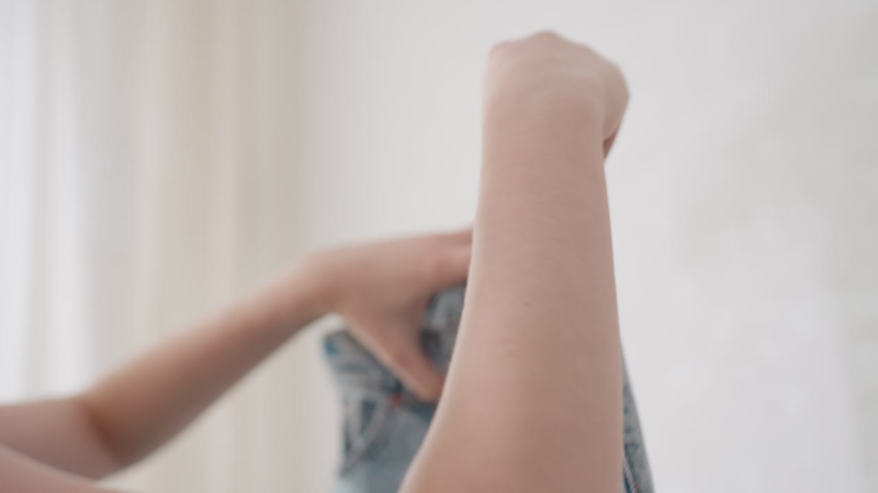 Close up hand view of woman gently folding jeans trouser with care showing detail of denim fabric household chore clothing maintenance lifestyle responsibility