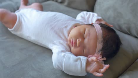 a wiggling newborn baby laying on a couch and getting sleepy