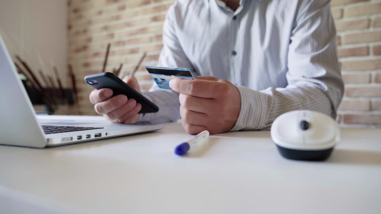 A man uses a smartphone for online shopping, enters credit card information.