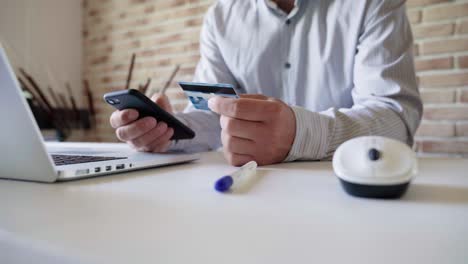 a man uses a smartphone for online shopping, enters credit card information.