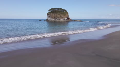 mujer en bikini recostada sobre una toalla y disfrutando de la vista de una pequeña isla frente a la costa de playa real en costa rica