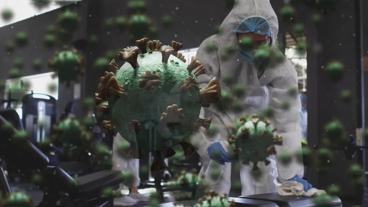 несколько клеток ковид-19 плавают над группой медицинских работников, очищающих тренажерный зал с помощью дезинфицирующего средства