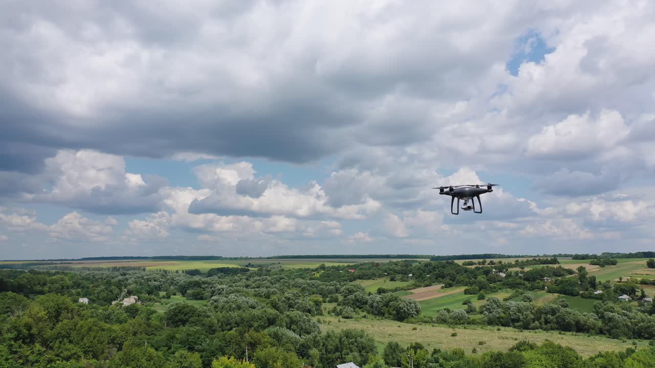 Drone overflying field. Drone quadcopter with digital camera flying over countryside