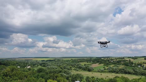 Drone overflying field. Drone quadcopter with digital camera flying over countryside