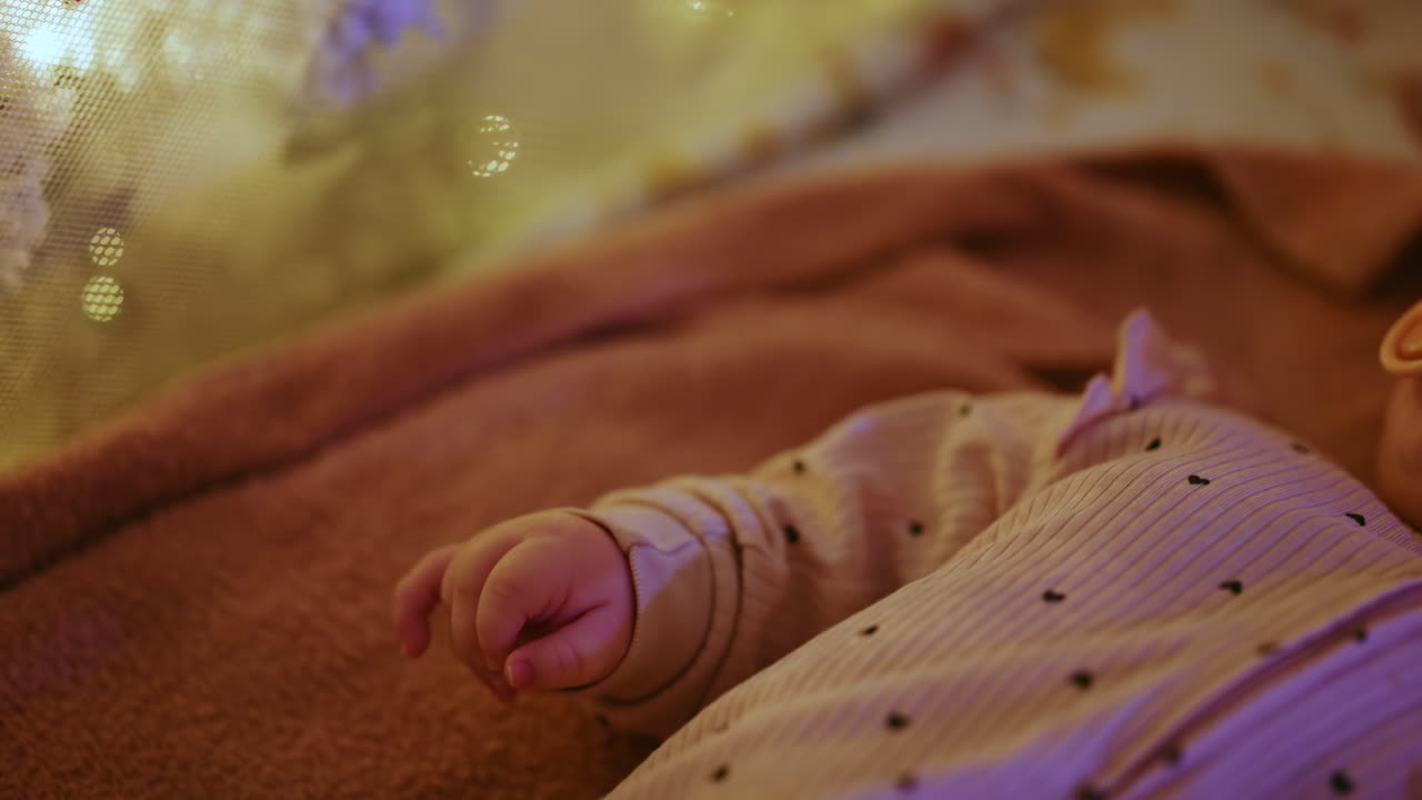 Close up of a baby's hand with warm Christmas lights in the background