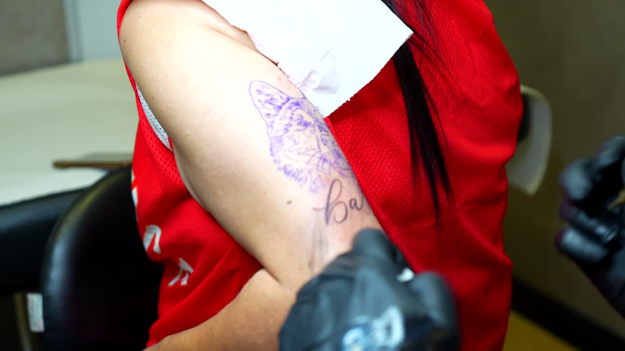 Tattoo artist applying some vaseline on the tracing before tattooing husky on upper arm