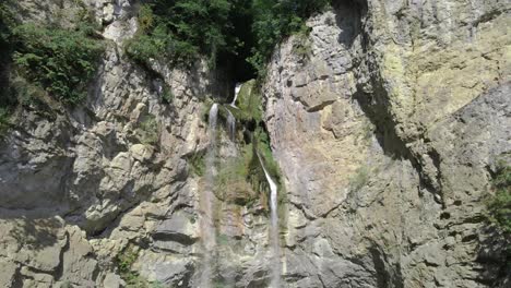 zoom de drones fuera de la cascada natural en la formación de los acantilados de las montañas rocosas
