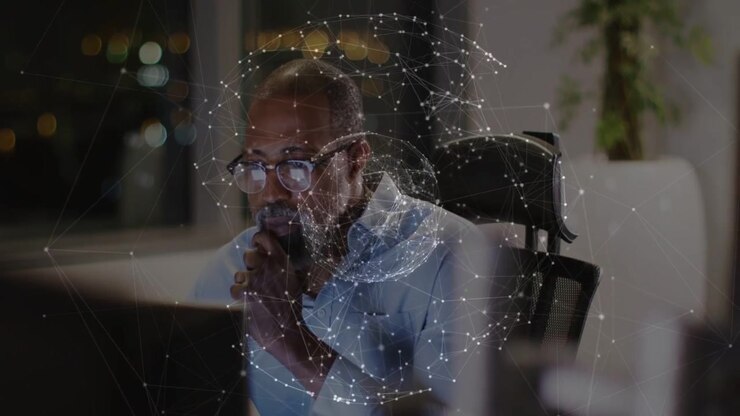 African American man working in office, studying rotating data globe on monitor, wearing eyeglasses