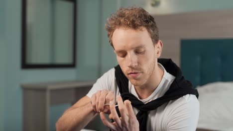 retrato de un hombre guapo cortando uñas con tijeras