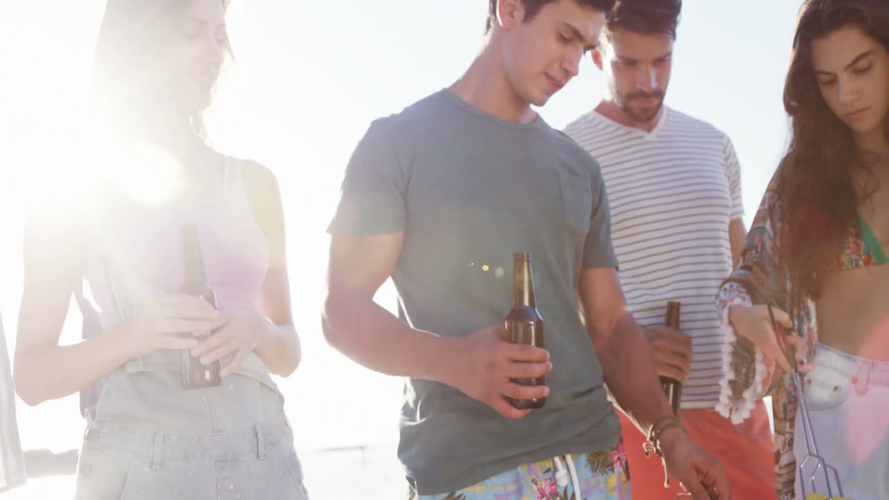 amigos cocinando comida en la barbacoa y bebiendo cerveza en la playa 4k