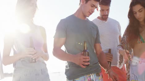 amigos cocinando comida en la barbacoa y bebiendo cerveza en la playa 4k