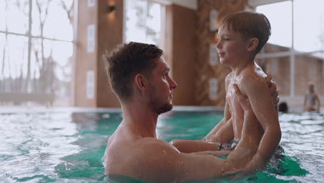 little boy and his father are swimming and playing in pool of modern hotel in weekend of vacation