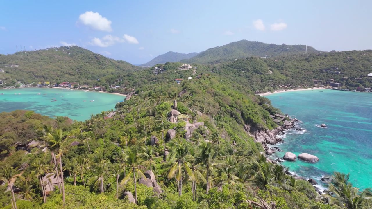 Panorama aéreo de colinas verdes exuberantes, costa rochosa e mar turquesa em um dia ensolarado.