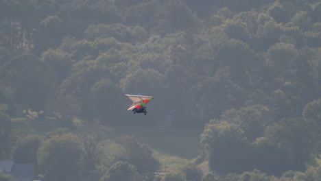 Drachenflug-Geht-Aus-Dem-Rahmen-Rechts-Mit-Bäumen-Und-Stadt-Darunter,-Tandem-Drachenfliegen