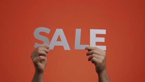 sale announcement. hands showing sale sign, close-up video on orange chromakey. store discounts. cheap shopping concept