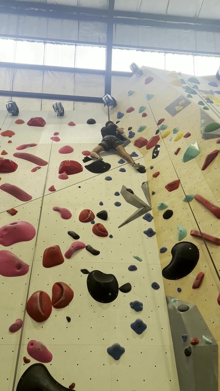 A climber nears the top of the colorful bouldering wall