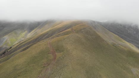 Drone-video-gravel-dirt-road-hills-foggy-mountain-Gramos-peaks-Greece-overcast