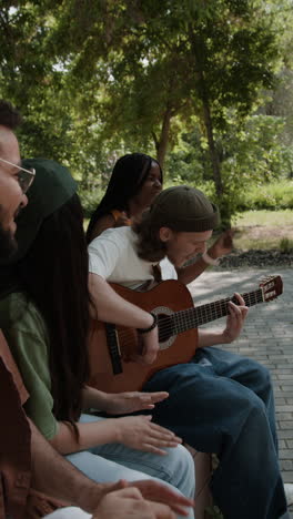 friends playing acoustic guitar in a park